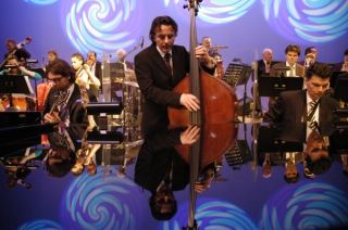 Muzikant met contrabas met op achtergrond orkest